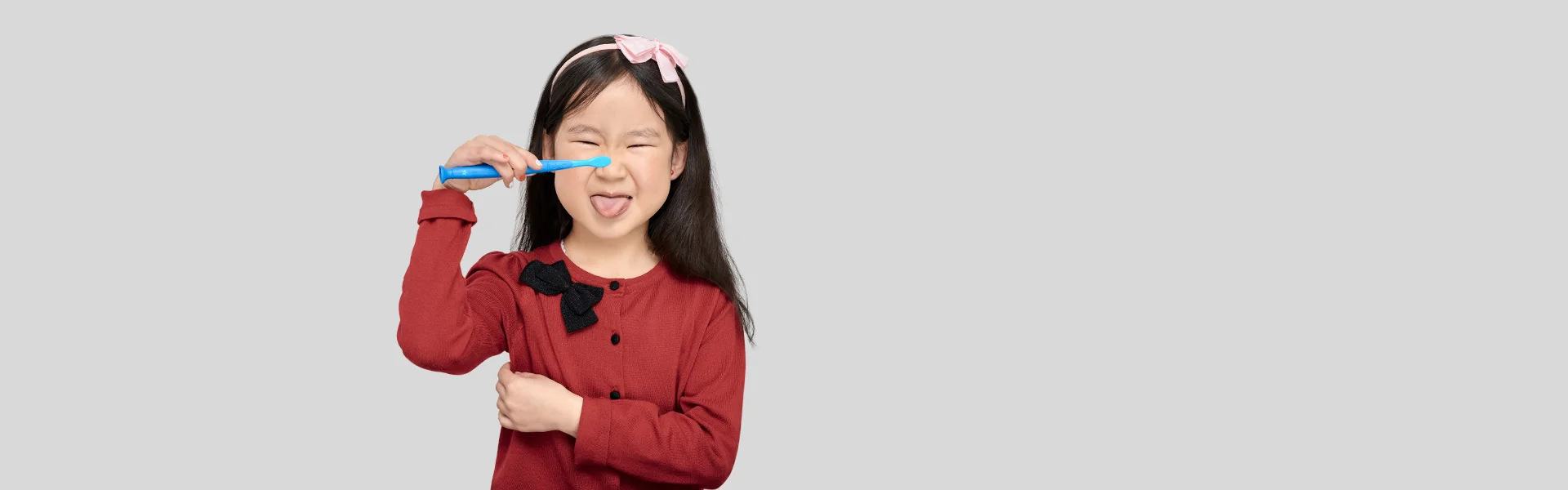 Kleines Mädchen mit Zahnbürste, streckt die Zunge heraus