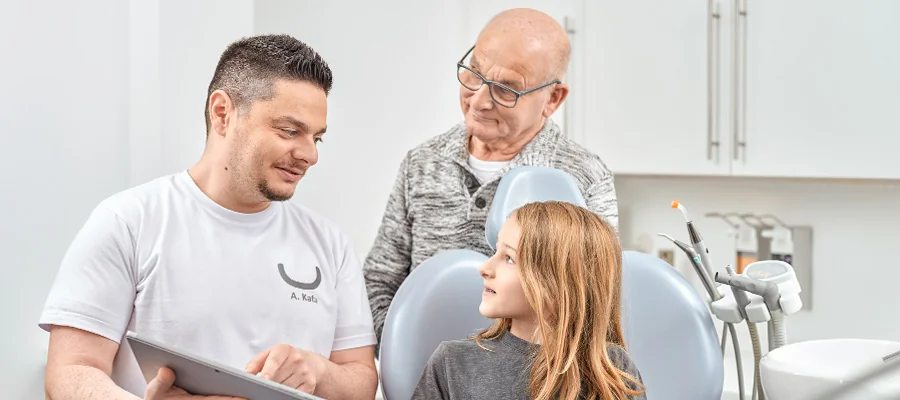 Behandler zeigt Großvater und Enkelin den Behandlungsplan auf einem Tablet